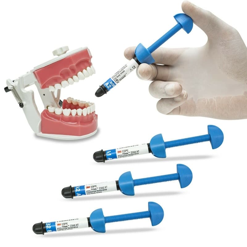 Premium 3M ESPE Filtek Z350 XT restorative composite kit in clinical use – dentist hand holding A2 body shade syringe next to dental typodont