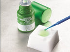 Tokuyama Shield Force Plus dental desensitizer application – 3mL green bottle open with cap removed, green liquid dispensed on white mixing pad, blue micro applicator brush picking up dental desensitizer – chairside application technique for dentists
